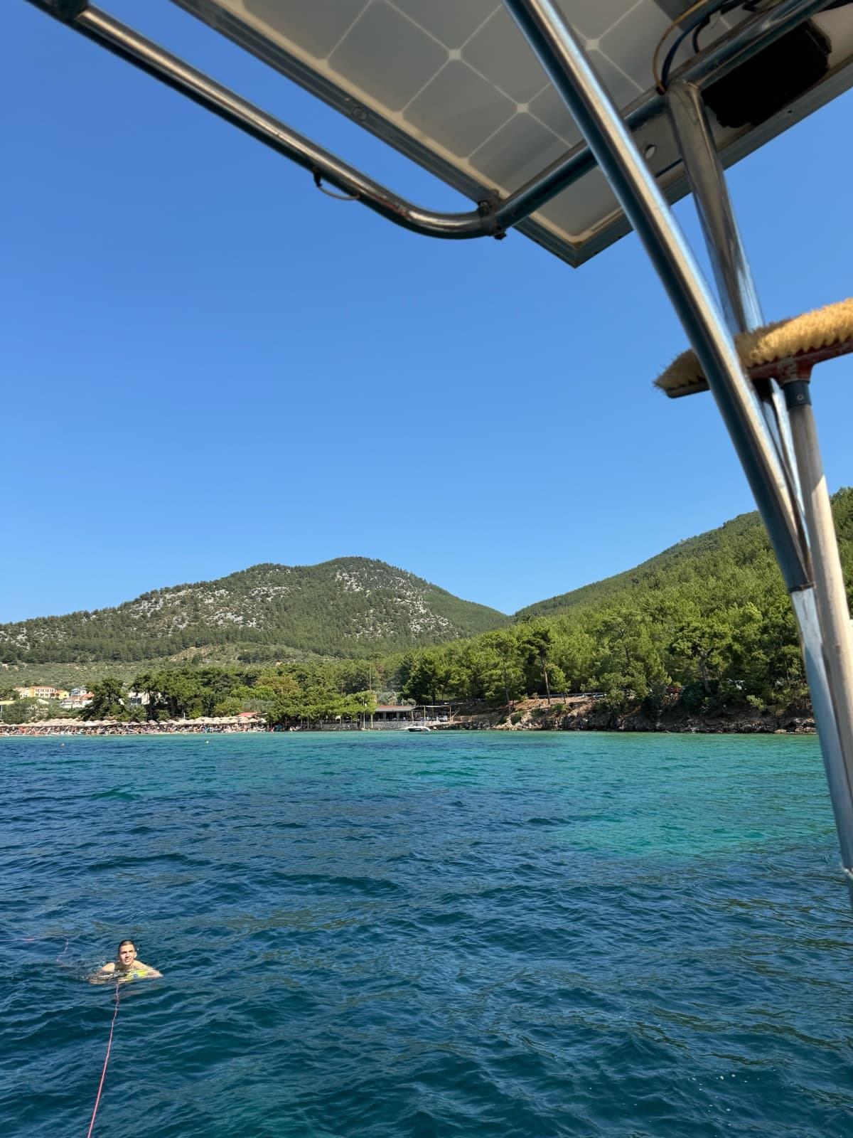 A guest swimming next to the yacht in a green bay